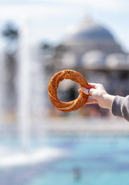 Güneşli bir günde arka planda bulanık cami ile kaplı susamlı ekmek geleneksel sokak yemeği kültürünü sembolize ediyor. İstanbul, Türkiye. 