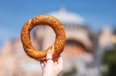 Güneşli bir günde arka planda bulanık cami ile kaplı susamlı ekmek geleneksel sokak yemeği kültürünü sembolize ediyor. İstanbul, Türkiye. 