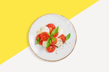 Domatesli taze Caprese salatası, beyaz sarı arka planda mozzarella ve fesleğen. Bir kafe veya restoran menüsü için reklam afişi. Sağlıklı beslenme konsepti. Üst görünüm, alanı kopyala.