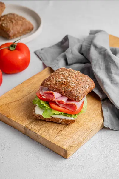 Prosciutto, peynir, domates, marul ve sostan yapılmış tahtadan yapılmış ekmek kızartma sandviçi. Sağlıklı ve diyet kahvaltı konsepti. Boşluğu kopyala.