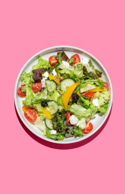 Sebze salatası, marul, sebze, zeytin ve parlak pembe arka planda gölgeli beyaz peynir. Afiş reklamı ya da menü düzeni için taze ve doğal sağlıklı gıda konsepti. Üst görünüm.