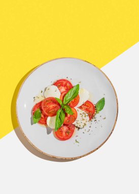 Domatesli taze Caprese salatası, beyaz sarı arka planda mozzarella ve fesleğen. Bir kafe veya restoran menüsü için reklam afişi. Sağlıklı beslenme konsepti. Üst görünüm, alanı kopyala.