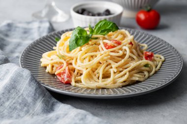 Kiraz domatesli kremalı spagetti, parmesan peyniri ve açık arkaplanda peçeteli fesleğen. İtalyan ya da Akdeniz mutfağı kavramı. 