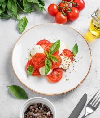Dilimlenmiş domatesli Caprese salatası, mozzarella ve taze sebze, yağ ve baharatlı fesleğen. Sağlıklı Akdeniz mutfağı konsepti. Üst görünüm.