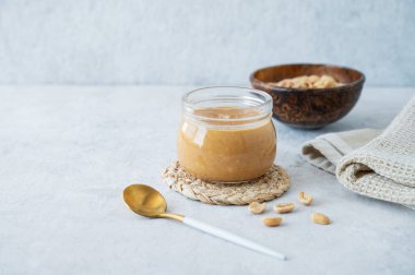 Cam kavanozda tuzlanmış fındık ve peçeteyle birlikte fıstık ezmesi. Kahvaltıda tatlı sandviçler için lezzetli ve sağlıklı atıştırmalık kavramı. Ön görünüm ve boşluk kopyala.