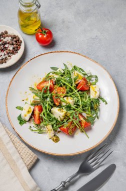 Kiraz domatesli Arugula salatası, mozzarella ve arka planda peçete ve çatal bıçaklı pesto sosu. Taze ve sağlıklı Akdeniz gıda konsepti. Üst görünüm, alanı kopyala.