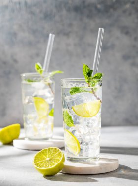 İki bardak mojito kokteyli, taze limonlu, naneli ve buzlu ve gölgeli. Turunçgil meyveli yaz ferahlatıcı içecek konsepti. Ön görünüm, boşluğu kopyala.