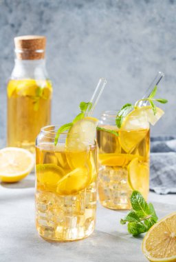 İki bardak ve limonlu buzlu içecek ve nane arkaplanlı, gölgeli ve narenciyeli. Bir yaz günü soğuk çay ya da limonata konsepti. Ön görünüm, boşluğu kopyala.