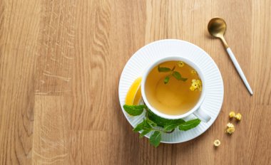 Limonlu, ballı ve nane şekerli bir fincan bitki çayı narenciye meyveli ve sabah ışığı. Kahvaltıda sağlıklı detoks içeceği kavramı. Üst görünüm, alanı kopyala.