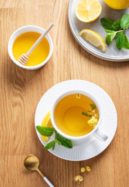 Limonlu, ballı ve nane şekerli bir fincan bitki çayı narenciye meyveli ve sabah ışığı. Kahvaltıda sağlıklı detoks içeceği kavramı. Üst görünüm.