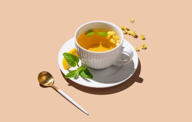 Limonlu bitki çayı ve bej arka planda naneli kaşık ve sabah gölgeleri. Reklam menüsü ya da afiş kafe için sağlıklı detoks içeceği kavramı. Boşluğu kopyala. 