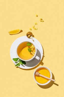 Limonlu bitki çayı, bal ve sabah gölgeli sarı arka planda nane. Reklam menüsü ya da afiş kafe için sağlıklı detoks içeceği kavramı. Üst görünüm, alanı kopyala. 