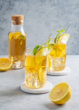İki bardak ve limonlu buzlu içecek ve nane arkaplanlı, gölgeli ve narenciyeli. Bir yaz günü soğuk çay ya da limonata konsepti. Ön görünüm, boşluğu kopyala.