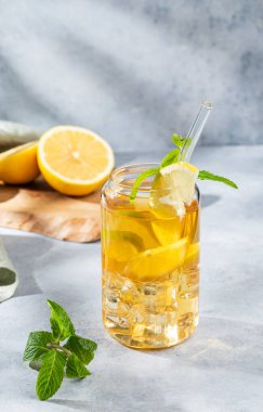 Limonlu buzlu içecek ve bir bardakta nane. Arka planda gölgeler ve narenciye meyveleriyle birlikte. Bir yaz günü soğuk çay ya da limonata konsepti. Ön görünüm, boşluğu kopyala.