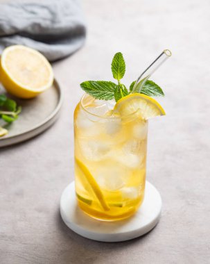 Limonlu buzlu çay ve narenciye arkaplanda hafif bir bardakta nane. Yaz günü ferahlatıcı içecek ya da limonata konsepti. Boşluğu kopyala.