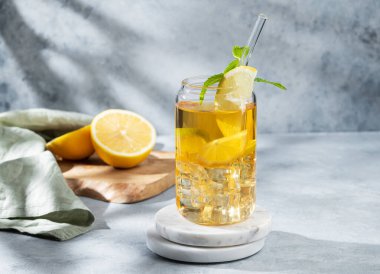 Limonlu buzlu içecek ve mermer bir bardakta nane. Arka planda, gölgeli ve narenciyeli bir tezgah. Bir yaz günü soğuk çay ya da limonata konsepti. Ön görünüm, boşluğu kopyala.