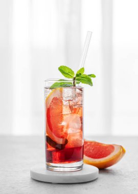 Greyfurt, nane şekeri ve buzlu bir bardakla taze bir kokteyl. Masanın üzerinde, pencereye karşı doğal ışık. Yaz turunçgilleri ya da limonata konsepti. Ön görünüm ve boşluk kopyala.