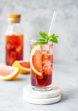 Şişesi ve doğal ışığı olan bir masada greyfurt, nane ve buzlu bir bardakla taze bir kokteyl. Yaz turunçgilleri ya da limonata konsepti. Ön görünüm ve boşluk kopyala.