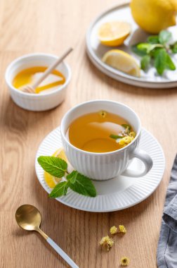 Limonlu, ballı ve nane şekerli bir fincan bitki çayı narenciye meyveli ve sabah ışığı. Kahvaltıda sağlıklı detoks içeceği kavramı. Üst görünüm.