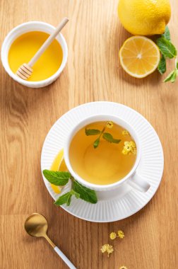 Limonlu, ballı ve nane şekerli bir fincan bitki çayı narenciye meyveli ve sabah ışığı. Kahvaltıda sağlıklı detoks içeceği kavramı. Üst görünüm.