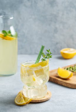 Taze limonlu limonata, kekik ve buzlu arka planda hafif bir şişe ve meyve. Modaya uygun bir yaz tatili konsepti limonlu mojito içeceği. Boşluğu kopyala.