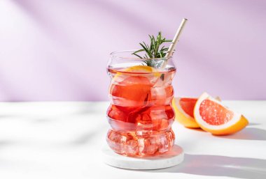 Beyaz pembe arka planda greyfurt, biberiye ve buzla mocktail tazeleyici. Yaz turunçgil içeceği ya da kafe reklamları için limonata konsepti. Ön görünüm, boşluğu kopyala.