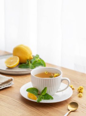 Limonlu, ballı ve nane şekerli bir fincan bitki çayı. Sabah ışıklarıyla pencereye yaslanmış narenciye meyveleriyle birlikte. Kahvaltıda sağlıklı detoks içeceği kavramı. Boşluğu kopyala.