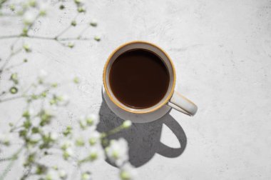 Bir fincan taze demlenmiş kahve ve açık dokulu arka planda sabah gölgeleri olan bir buket çingene çiçeği. Estetik kahvaltı içeceği konsepti. Üst görünüm ve kopyalama alanı.