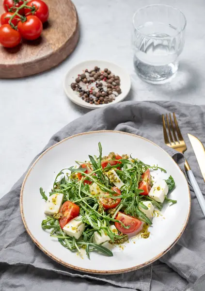 Kiraz domatesli sağlıklı roka salatası, mozzarella ve taze sebzelerle kaplı hafif dokulu bir tabakta pesto sosu. Taze ve sağlıklı Akdeniz gıda konsepti. Üst görünüm.