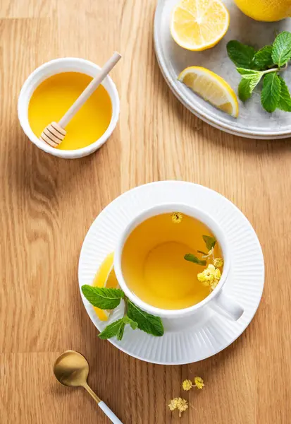 Limonlu, ballı ve nane şekerli bir fincan bitki çayı narenciye meyveli ve sabah ışığı. Kahvaltıda sağlıklı detoks içeceği kavramı. Üst görünüm.