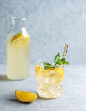 Limonlu taze limonata, naneli ve buzlu buzlu mavi arka planda şişe. Yaz modasına uygun mojito mocktail konsepti. Ön görünüm