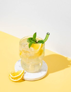 Limonlu mocktail mojito, naneli ve buzlu. Beyaz sarı arka planda beyaz limonata. Barın reklam ve afişi için yaz modasına uygun içki konsepti. Boşluğu kopyala.