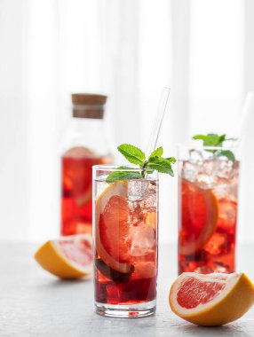 İki bardak kokteyl, greyfurt, nane ve buzlu bir masa üzerinde doğal ışık, şişe ve narenciye meyveleri olan bir pencere. Yaz içeceği ya da limonata konsepti. Ön görünüm ve boşluk kopyala.