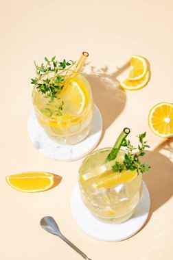 İki bardak mocktail mojito, limon, limon, kekik ve buz. Sarı arka planda meyveli turunçgil limonatası. Yaz modasına uygun soğuk içecek konsepti. Üst görünüm, alanı kopyala.