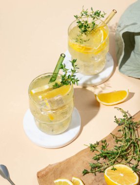 İki bardak mocktail mojito, limon, limon, kekik ve buz. Sarı arka planda meyveli turunçgil limonatası. Yaz modasına uygun soğuk içecek konsepti. Üst görünüm, alanı kopyala.