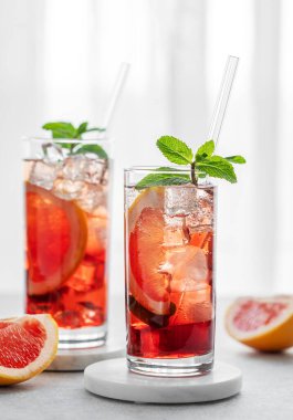 İki bardak kokteyl, greyfurt, nane ve buzlu bir masaya karşı doğal ışık ve narenciye meyveleri. Yaz içeceği ya da limonata konsepti. Ön görünüm ve boşluk kopyala.