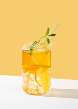 Beyaz bej arka planda gölgeli bir bardakta limonlu buzlu çay ve nane şekeri. Yaz günü ferahlatıcı içecek ya da limonata konsepti. Ön görünüm, boşluğu kopyala.