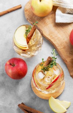 İki bardak soğuk elma kokteyli ya da tarçın ve kekik ile süslenmiş buzlu elma şarabı hafif bir arka planda meyve dilimleriyle. Ferahlatıcı içecek konsepti. Üst görünüm.