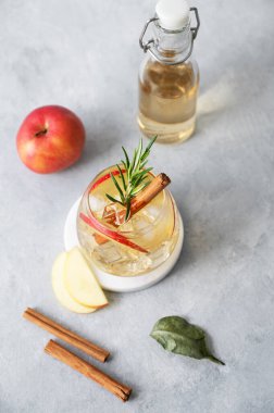 Elma kokteyli ya da buzlu elma şarabı, tarçın ve biberiyeyle süslenmiş mermer tezgahta meyve ve şişeyle birlikte. Ferahlatıcı içecek konsepti. Üst görünüm, alanı kopyala