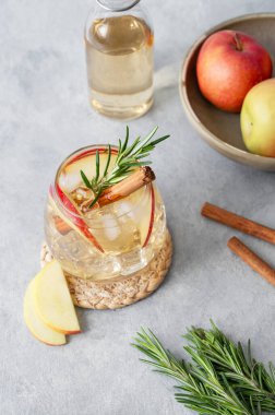 Elma kokteyli ya da buzlu elma şarabı, tarçın ve biberiyeyle süslenmiş hafif bir arka planda meyve ve şişeyle. Ferahlatıcı içecek konsepti. Üst görünüm