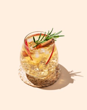 Elma kokteyli ya da buzlu, tarçınlı ve gölgeli bej bir arka planda biberiyeli elma şarabı. Reklamcılık ya da bar menüsü afişi için canlandırıcı içecek konsepti. Boşluğu kopyala