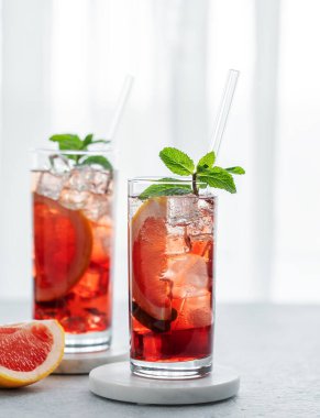 İki bardak kokteyl, greyfurt, nane ve buzlu bir masaya karşı doğal ışık ve narenciye meyveleri. Yaz içeceği ya da limonata konsepti. Ön görünüm ve boşluk kopyala.