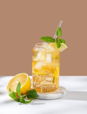 Limonlu buzlu çay ve beyaz bej arka planda bir bardakta nane ve narenciye ve otlarla birlikte. Yaz günü ferahlatıcı içecek ya da limonata konsepti. Ön görünüm, boşluğu kopyala.