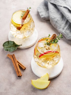 İki bardak soğuk elma kokteyli ya da tarçın ve kekik ile süslenmiş buzlu elma şarabı hafif bir arka planda mermer tezgahta meyve dilimleriyle. Ferahlatıcı içecek konsepti. Üst görünüm.