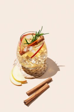 Elma kokteyli ya da buzlu, tarçınlı ve gölgeli bej bir arka planda biberiyeli elma şarabı. Reklamcılık ya da bar menüsü afişi için canlandırıcı içecek konsepti. Boşluğu kopyala