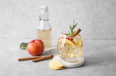 Elma kokteyli ya da buzlu elma şarabı, tarçın ve biberiyeyle süslenmiş mermer tezgahta meyve ve şişeyle birlikte. Ferahlatıcı içecek konsepti. Ön görünüm, boşluğu kopyala