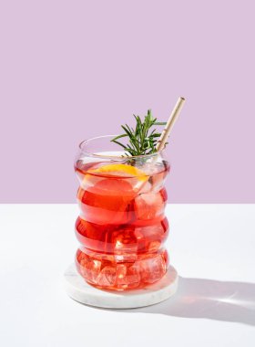 Beyaz pembe arka planda gölgeli bir bardakta greyfurt, biberiye ve buzla mocktail tazeleyici. Yaz turunçgil içeceği ya da kafe reklamları için limonata konsepti. Ön görünüm