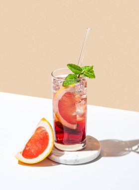 Greyfurt, nane ve buzlu beyaz sarı arka planda gölgesi ve narenciye dilimli bir bardakta taze bir kokteyl. Yaz içeceği ya da limonata konsepti. Üst görünüm ve kopyalama alanı.