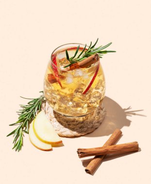 Elma kokteyli ya da buzlu, tarçınlı ve gölgeli bej bir arka planda biberiyeli elma şarabı. Reklamcılık ya da bar menüsü afişi için canlandırıcı içecek konsepti. Boşluğu kopyala