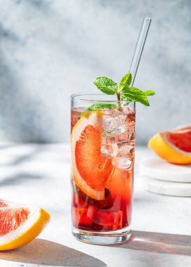 Hafif dokulu arka planda gölgesi ve narenciye meyvesi olan bir bardakta greyfurt, nane ve buz ile ferahlatıcı bir kokteyl. Yaz içeceği ya da limonata konsepti. Ön görünüm, boşluğu kopyala.